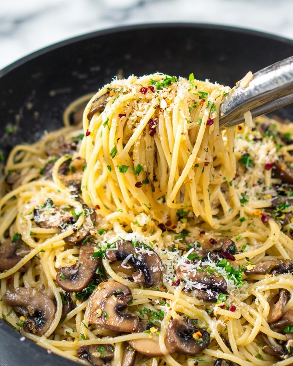 The image shows a close-up of a black pan filled with spaghetti pasta mixed with sliced brown mushrooms, sprinkled with chopped green herbs and red chili flakes. The pasta strands are light yellow and slightly shiny, coated with oil or sauce. There are thin layers of grated white cheese scattered over the top. A metal tong held by a woman's hand lifts a portion of the pasta, revealing the mix of mushrooms and herbs throughout. The background shows a white marbled surface out of focus. photo taken with an iphone --ar 4:5 --v 7