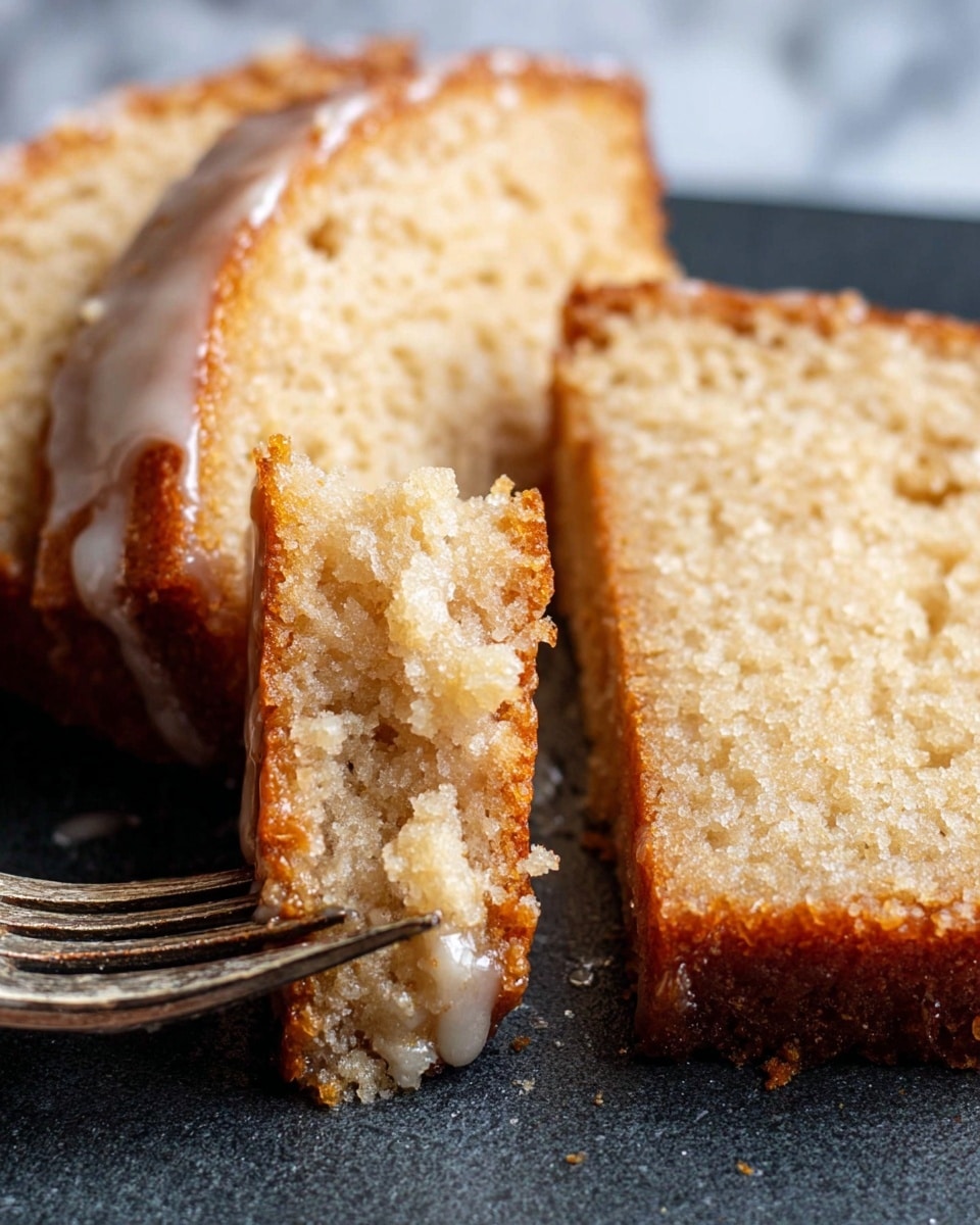 Two slices of light brown cake with a moist texture are placed on a dark surface. The cake has a thin, slightly golden crust around the edges. A fork is holding a small piece of the cake, showing the soft, crumbly texture inside. There are small shiny spots of glaze on the surface of the cake, adding a slight shine. The background is a white marbled texture. photo taken with an iphone --ar 4:5 --v 7