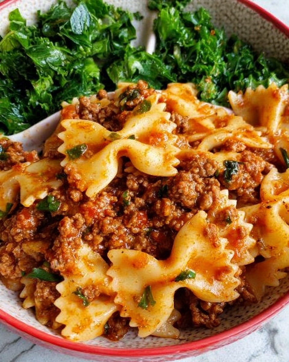 The image shows a white divided plate on a white marbled surface holding two types of food. On the larger section, there is a serving of pasta with bowtie shapes, covered in a thick meat sauce with ground beef and small bits of herbs mixed in. The pasta is coated with a reddish-brown sauce giving it a slightly shiny texture. On the smaller section of the plate, there is a portion of chopped green leafy vegetables, bright and fresh in color with a slightly rough texture. Photo taken with an iphone --ar 4:5 --v 7