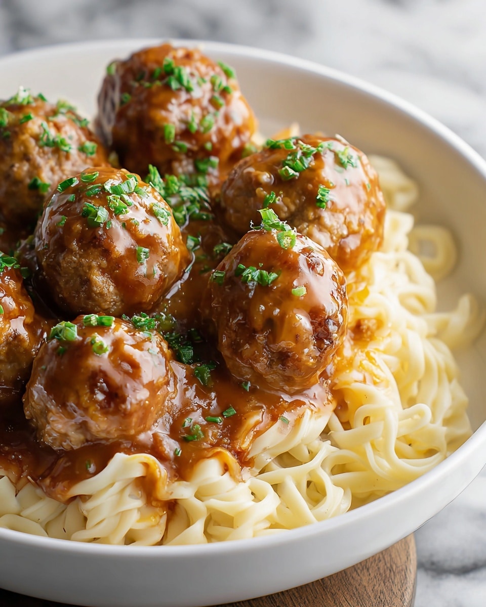 A white bowl filled with three layers: the bottom layer is light yellowish noodles with a soft texture placed in the bowl's base, the middle layer is thick reddish-brown sauce spread over the noodles, and the top layer consists of several round meatballs with a golden-brown crust, each covered with light brown gravy and sprinkled with small bright green chopped herbs. The setting includes a white marbled textured surface beneath the bowl. photo taken with an iphone --ar 4:5 --v 7