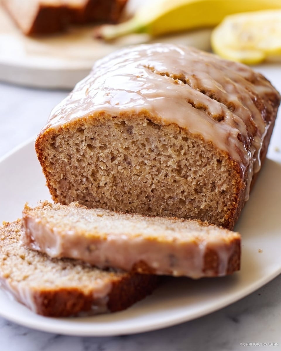 A loaf of banana bread is cut into thick slices and placed on a white plate. The banana bread has a light brown crumb with a slightly coarse texture, showing bits of banana inside. The top of the bread is covered with a shiny, pale glaze that has some small cracks and smooth, glossy areas. One sliced piece is leaned against the main loaf, showing the soft inside, while the rest of the loaf sits flat on the plate. In the background, there is a blurred white marbled surface with a partly visible banana. Photo taken with an iphone --ar 4:5 --v 7