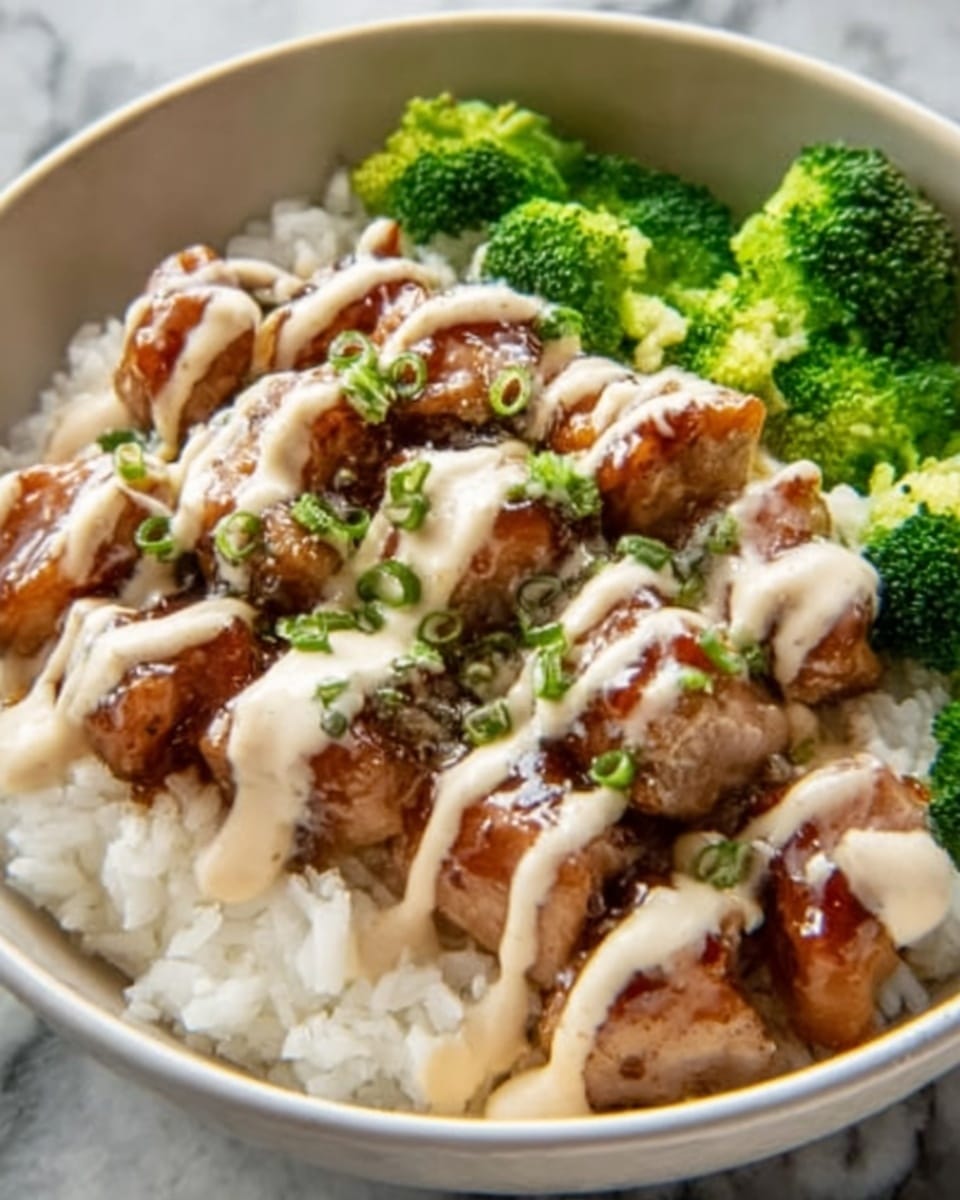 A white bowl holds a dish with three main layers: the bottom layer is white rice with a soft, fluffy texture; on top are evenly cut, glazed brown meat pieces covered by a thick, light beige creamy sauce drizzled in neat lines; bright green broccoli florets are placed around the edges, creating a fresh contrast. The bowl sits on a white marbled surface. Photo taken with an iphone --ar 4:5 --v 7