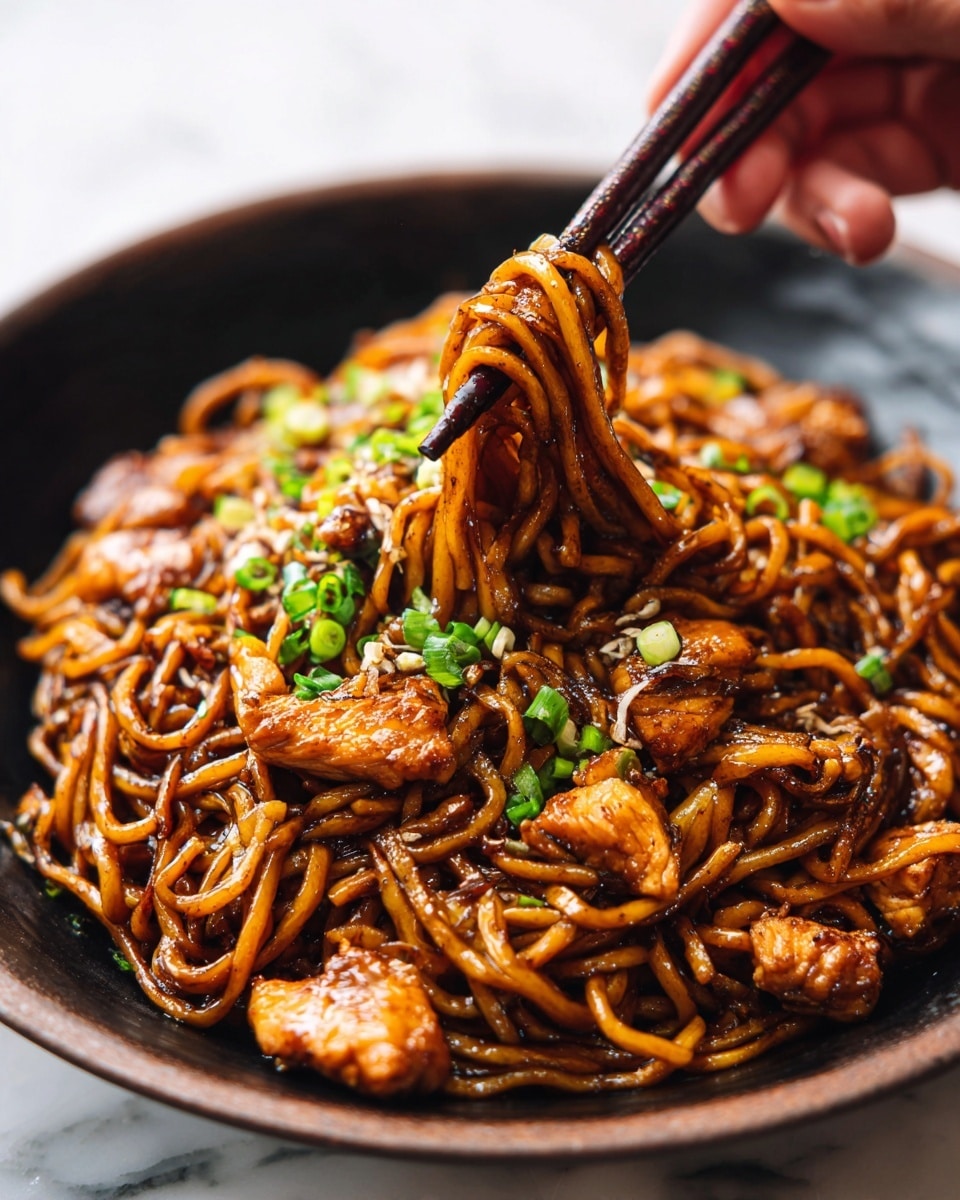 A close-up view of a black bowl filled with thick, glossy noodles coated in a rich, dark brown sauce, mixed with pieces of cooked chicken and sprinkled with finely chopped green onions. The chicken pieces are golden brown and tender, sitting evenly throughout the noodles. A woman's hand holding dark wooden chopsticks is lifting a small bundle of noodles from the bowl, emphasizing the texture and sauciness of the dish. The bowl rests on a white marbled surface. photo taken with an iphone --ar 4:5 --v 7